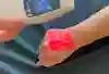 Bild visar en venskanner som lyser med infrarött ljus på ovansidan av en hand så att kärl syns