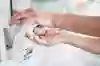 Bilden visar två händer som tar en klick handdesinfektion ur en pumpflaska.